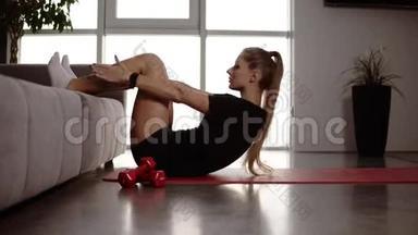 漂亮的女运动员在工作上练习腹部，按压摇动。 在家里的沙发上进行按压练习